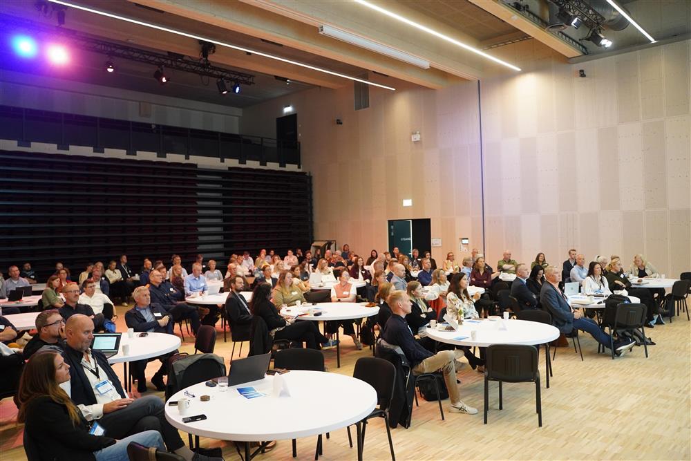 Salen i Campus Kristiansund satt opp med runde bor og full av folk - Klikk for stort bilde