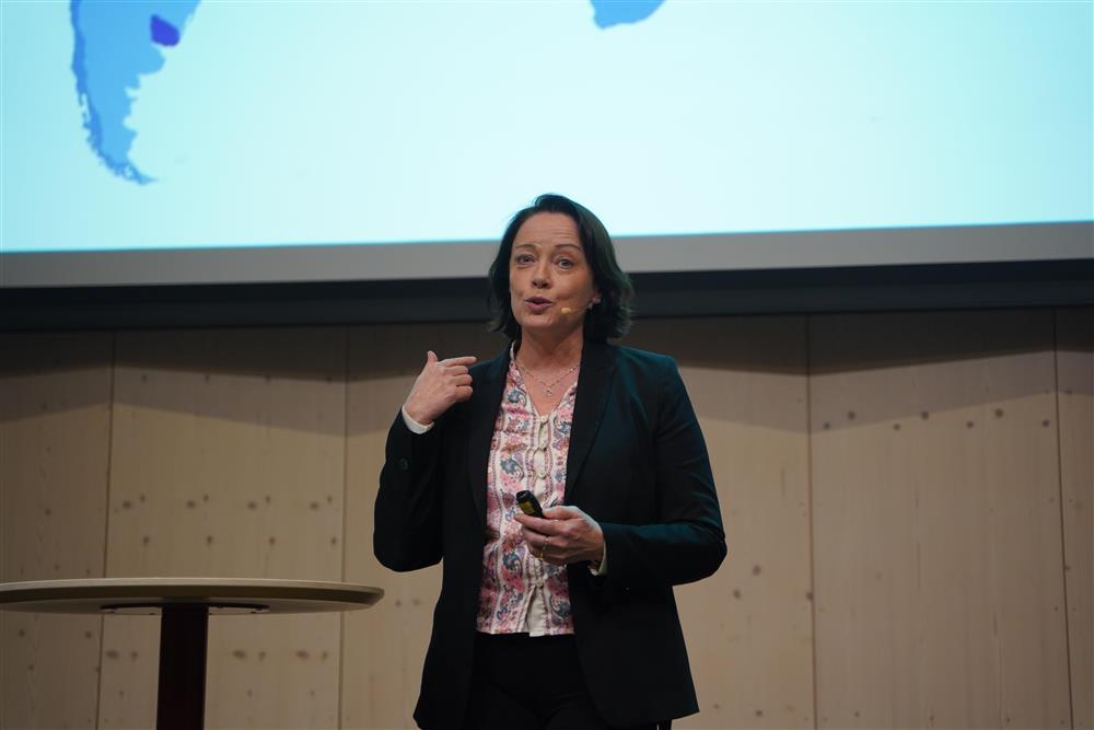 Dame snakker inn i kamera og banker hånden i den andre hånden - Klikk for stort bilde